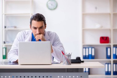 Klinikte çalışan genç erkek doktor.