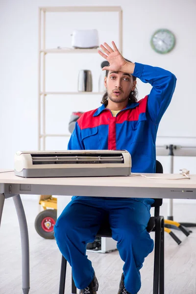 Jonge mannelijke aannemer repareert airconditioner in werkplaats — Stockfoto
