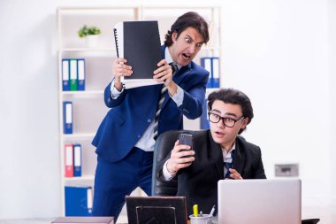 Patron ve erkek asistanı ofiste çalışıyor.