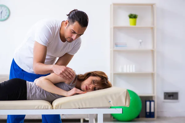 Mujer joven que visita al médico fisioterapeuta masculino — Foto de Stock