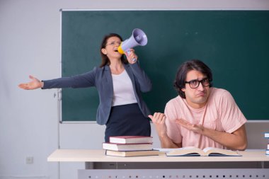 Yaşlı bayan öğretmen ve erkek öğrenci sınıfta.