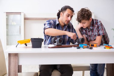 Genç baba oğluyla kaykay tamir ediyor.