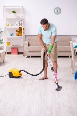 Genç yaralı adam evi temizliyor.