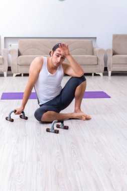 Genç adam evde antrenman ve egzersiz yapıyor.