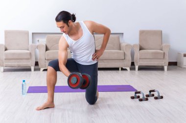 Genç adam evde antrenman ve egzersiz yapıyor.