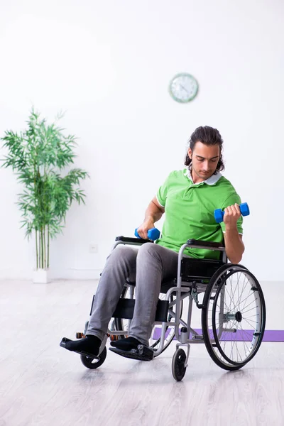 Mladý muž na kolečkovém křesle cvičení uvnitř — Stock fotografie