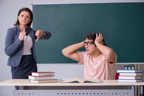 Old female teacher and male student in the classroom — Stock Photo, Image