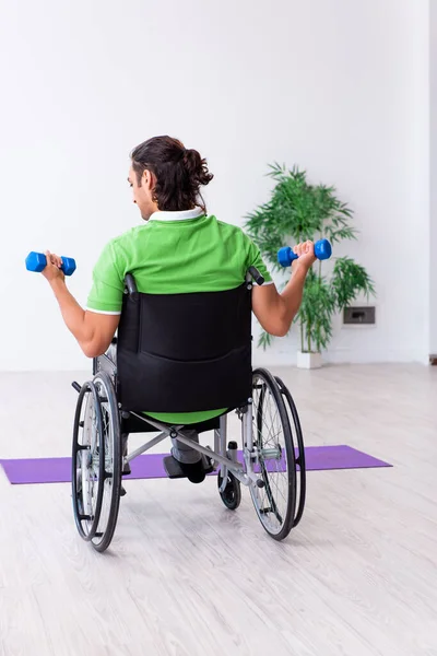 Młody mężczyzna na wózku inwalidzkim ćwiczy w pomieszczeniu — Zdjęcie stockowe