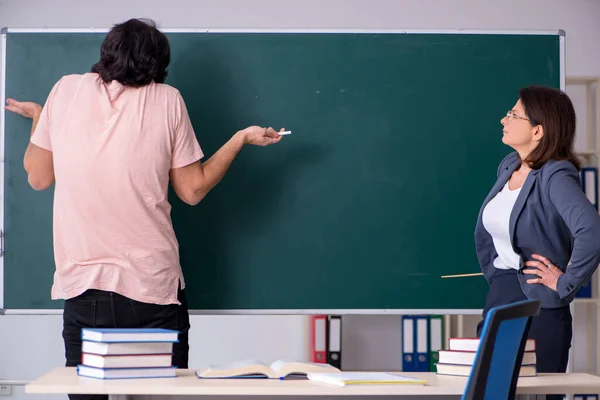 Old female teacher and male student in the classroom — Stock Photo, Image