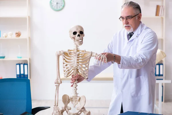 Médico varón envejecido con esqueleto — Foto de Stock