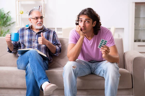 Jonge student en zijn oude opa thuis — Stockfoto