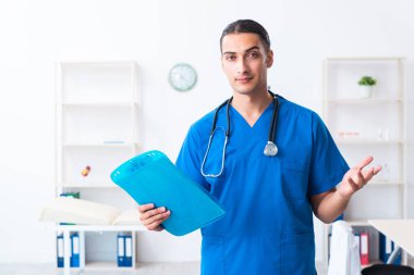Klinikte çalışan genç erkek doktor.