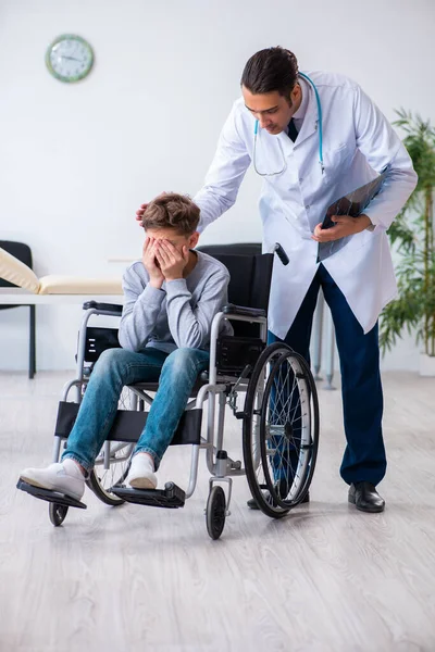 Genç erkek doktor pediatrist ve tekerlekli sandalyedeki çocuk. — Stok fotoğraf