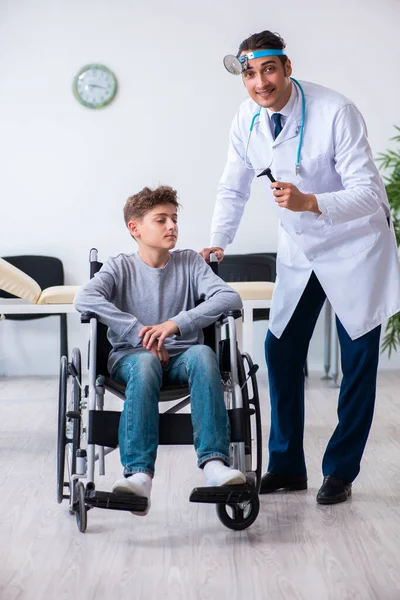 Молодий чоловік лікар педіатр і хлопчик в інвалідному кріслі — стокове фото