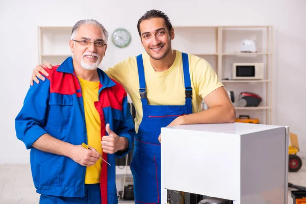 Dois empreiteiros reparando geladeira na oficina — Fotografia de Stock