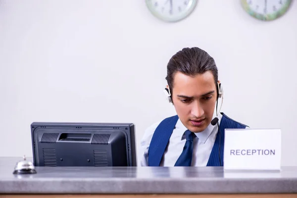 Young man receptionist at the hotel counter