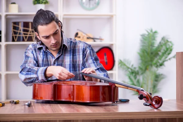 Jeune beau réparateur réparer violoncelle — Photo