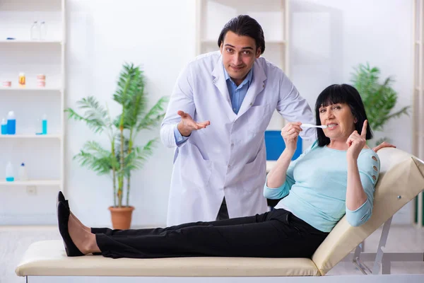 Vecchia visitando giovane medico dentista — Foto Stock