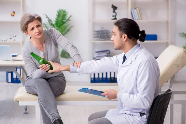 Kvinnlig alkoholist besöker ung manlig läkare — Stockfoto