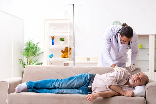 Young male doctor visiting old patient at home — Stock Photo, Image