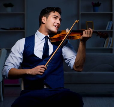 Genç müzisyen evde keman çalıyor.