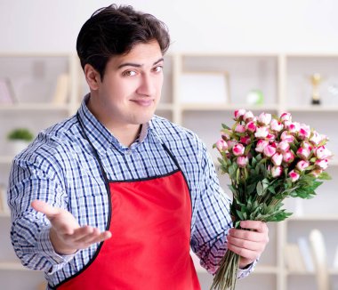 Çiçekçi asistanı bir demet çiçek veriyor.