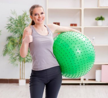 Spor salonunda denge topuyla egzersiz yapan genç bir kadın.