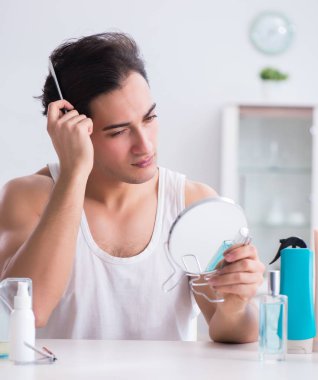 Genç yakışıklı adam aynaya bakıyor.