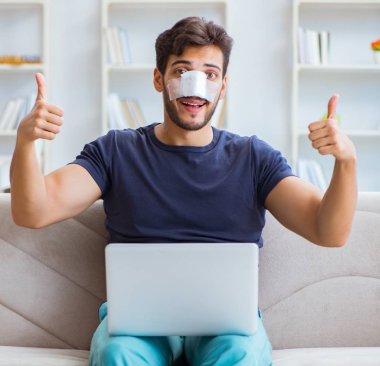 Genç adam estetik cerrahi burnundan sonra evde iyileşiyor.