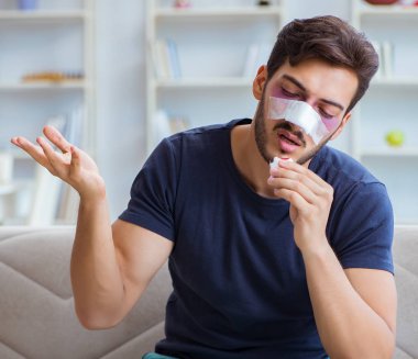Genç adam estetik cerrahi burnundan sonra evde iyileşiyor.