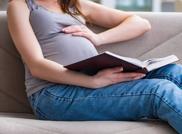 Mujer embarazada con barriga sentada en un sofá en casa — Foto de Stock