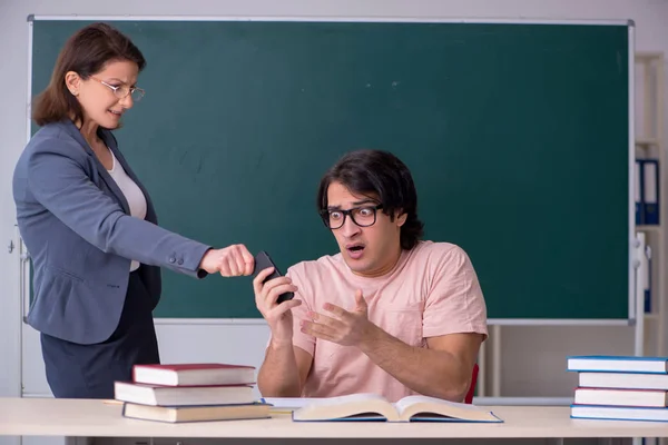 Gammal kvinnlig lärare och manlig student i klassrummet — Stockfoto