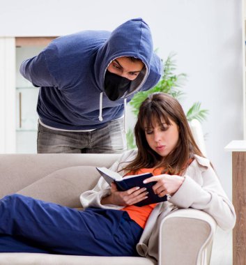 Silahlı adam evde genç bir kadına saldırıyor.