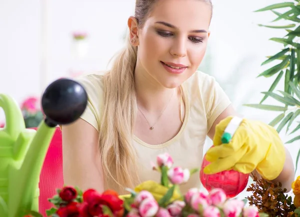 Jonge vrouw water geven planten in haar tuin — Stockfoto