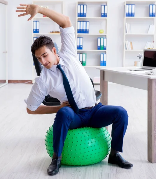 Young businessman doing sports stretching at workplace — Stock Photo, Image