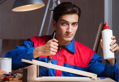 Genç adam ahşap parçaları diy konseptinde yapıştırıyor.