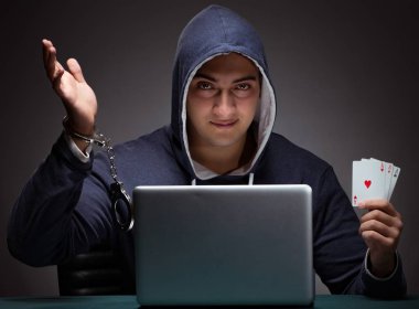 Elleri kelepçeli kapüşonlu genç bir adam Los Angeles 'ın önünde oturuyor.