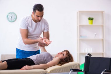 Genç bir kadın erkek doktor fizyoterapisti ziyaret ediyor.