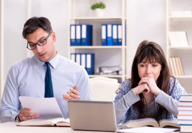 Erkek öğretim görevlisi bayan öğrenciye ders veriyor.