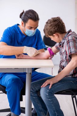 Genç çocuk hastanede doktoru ziyaret ediyor.