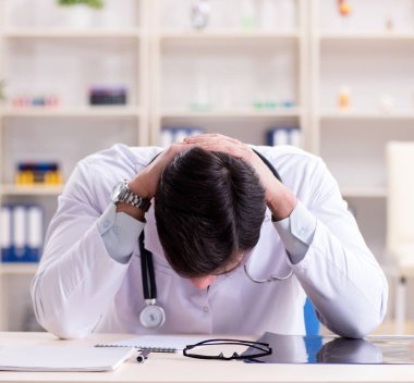 Genç doktor ofiste oturuyor.