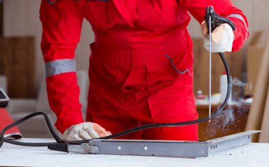 Kaynak tabancası elektrot ve kask takan genç bir tamirci.