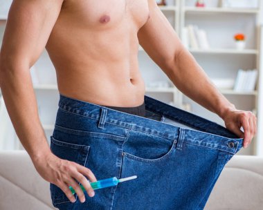 Kilo verme konseptinde büyük beden pantolon giyen bir adam.