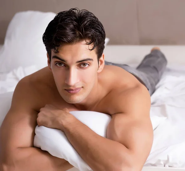 Junge hübsche hemdlose Kerl zeigt nackten Oberkörper sexy auf Bett bei h — Stockfoto