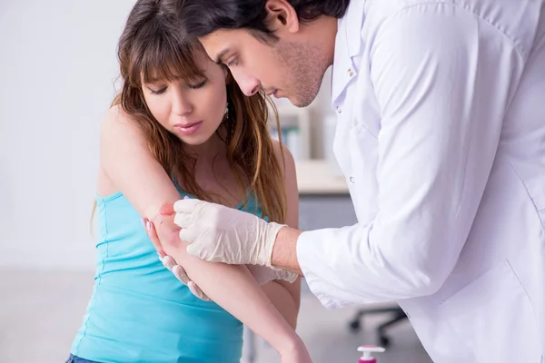 Jovem braço ferido mulher visitando jovem médico traumatologista — Fotografia de Stock