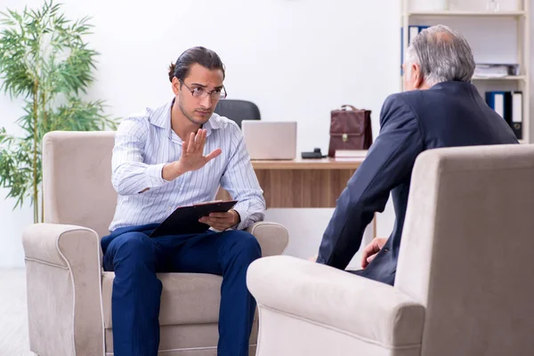 Oude man op bezoek bij jonge mannelijke dokter psycholoog — Stockfoto