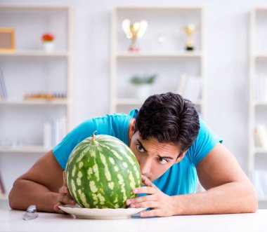 Evde karpuz yiyen bir adam.