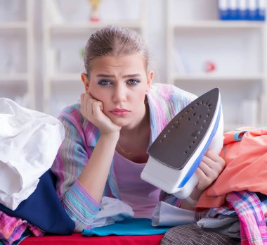 Üzücü kadın evde kıyafetleri ütülüyor.