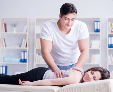 Genç doktor kayropraktik uzmanı kadın hastaya masaj yapıyor.