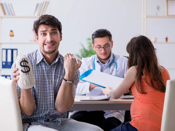 Pregnant woman with her husband visiting the doctor in clinic — Stock Photo, Image